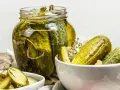 Vaso di cetriolini in agrodolce, con alcuni in una ciotola. Perfetti per un antipasto croccante e saporito.