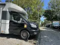 Husbil parkerad på en campingplats vid frankrike kust. Soligt väder med träd och andra husbilar i bakgrunden.