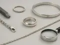 Gioielli in argento 925: anelli, bracciale, catena e punzone. La qualità è visibile anche con una lente d'ingrandimento.