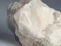 Surowy, biały alabaster o matowej powierzchni, z delikatnymi, kremowymi przebarwieniami.