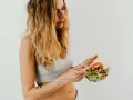 Donna con capelli biondi mangia un'insalata fresca, parte della sua vlckd dieta.
