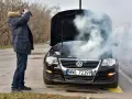 Mężczyzna z przerażeniem patrzy na dymiący silnik swojego Volkswagena. To typowe objawy zatarty silnik.