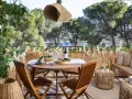 Encantadora decoracion terrazas con mesa de madera, sillas, banco y mucha vegetación. Un oasis verde para disfrutar del aire libre.