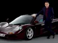 Rowan Atkinson w garniturze opiera się o swój bordowy McLaren F1. To jeden z jego ulubionych samochodów.