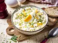 Cremiger Eiersalat mit Gurken und Kräutern, garniert mit einem Ei-Viertel. Ein köstliches eiersalat rezept für jede Gelegenheit.