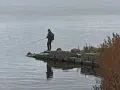 Wędkarz na kamienistym brzegu łowi ryby na spinning. Zastanawia się, jakie ryby na spinning mogą dziś brać.
