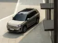 Szary elektryczny SUV GAC Aion V z czarnym dachem i relingami, zaparkowany na zewnątrz.