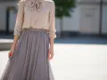 Elegancka beżowa bluzka z kokardą i szara długa spódnica. Idealna stylizacja, która odpowiada na pytanie: jaka bluzka do długiej spódnicy.