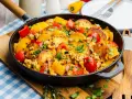Herzhafte bauernpfanne mit kartoffeln und ei, garniert mit frischer Petersilie und bunten Paprikastücken. Ein deftiges Gericht direkt aus der Pfanne.