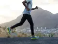 Un homme court sur une route, profitant d'un exercice cardio avec une vue sur la ville et les montagnes.