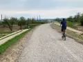 Mężczyzna na rowerze przemierza nową ścieżkę rowerową w Skawinie. W tle widać przemysłowe kominy i zielone tereny.
