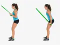 Kvinnlig atlet utför triceps pushdown med ett grönt träningsband.