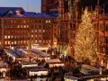 A bustling Christmas market in Munich, Germany, with a towering, illuminated tree and snow-dusted stalls.