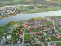 Widok z lotu ptaka na malownicze jezioro Pniewy otoczone zielenią i zabudowaniami.