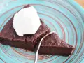 Pyszne keto brownie z cukinii, podane z bitą śmietaną na turkusowym talerzu. Idealne na deser bez wyrzutów sumienia.