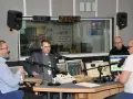 W studiu radiowym czterech mężczyzn, w tym ksiądz i osoba w jarmułce, rozmawia przy mikrofonach. W tle widać zegar i logo RDC.