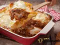 Pyszna, gorąca lasagne z mięsem mielonym i ciągnącym serem, właśnie nakładana drewnianą łopatką. Idealna na rodzinny obiad.