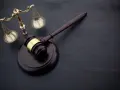 Wniosek o zamianę prac społecznych na potrącenie z wynagrodzenia wzór. Młotek sędziowski i waga sprawiedliwości na ciemnym tle.