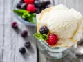 Cremiges Joghurteis selber machen: Eine Portion mit frischen Beeren und Minze, daneben eine Schüssel voller Brombeeren und Himbeeren.