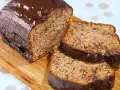 Saftiger Kuchen mit Bananen und Schokoladenglasur, auf einem Holzbrett serviert.