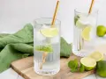 Erfrischende Drinks: Zwei Gläser mit Eis, Limettenscheiben und goldenen Strohhalmen. Perfekt zum **Wodka mischen** an einem warmen Tag.