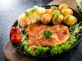 Schabowy smażony na smalcu a na oleju roślinnym, podany z ziemniakami, surówką i pomidorkami.