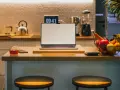 Ein Laptop steht auf einer Küchentheke neben Obst und einem Glas Tee. Vielleicht fragst du dich, was Bixby ist – ein digitaler Assistent, der dir bei vielen Dingen helfen kann.
