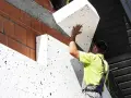 Budowlaniec montuje płyty styropianowe, tworząc skuteczną izolację termiczną budynku.