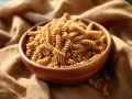 Misternie skręcone fusilli z kukurydzy w drewnianej misce. Makaron bezglutenowy kukurydziany kontra ryżowy – wybór dla zdrowia.