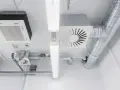 Detalles de sistemas de ventilación y extracción de aire, incluyendo conductos metálicos, unidades de aire acondicionado y luces fluorescentes en un techo.