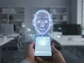 Dłoń trzyma smartfon, z którego wyłania się holograficzna głowa robota. To zaawansowany chatbot, otoczony ikonami komunikacji, gotowy do rozmowy.