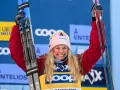 Uśmiechnięta narciarka z nartami w górze, świętuje sukces w biegach narciarskich. Klasyfikacja generalna FIS Cross Country World Cup.