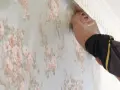 Händer som tapetserar med papperstapet med blommönster.