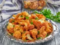 Chrupiący kalafior w panko, podany na ozdobnej tacy, posypany świeżą natką pietruszki. Idealna przekąska!