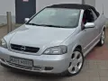 Silberner Opel Astra Bertone Cabrio mit offenem Verdeck, bereit für eine Spritztour.