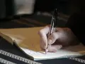 Dłoń pisze długopisem na kartce. Może to być ważny dokument, jak umowa dożywocia, podpisany w spokoju.