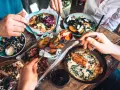 Leckeres Essen in einem Restaurant in Berlin Mitte: Pizza, Lachs, Rippchen und Salate werden von mehreren Händen geteilt.