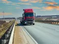Czerwona ciężarówka jedzie autostradą. Ubezpieczenie kabotażowe zapewnia spokój podczas międzynarodowych transportów.