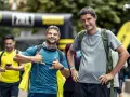 Zwei Männer mit Rucksäcken, einer mit Daumen hoch, der andere mit Handzeichen. Sie sind bereit für ihr Abenteuer, bei dem die richtige **Merinowolle Pflege** wichtig ist.