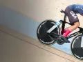 A determined track cyclist in a USA kit races on a wooden velodrome, pushing hard for victory.