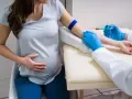 Ciężarna kobieta przechodzi badanie krzywej cukrowej. Pielęgniarka pobiera krew z żyły.