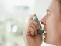 Mężczyzna używa inhalatora benodil, by złagodzić objawy astmy.