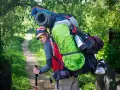Un randonneur, prêt pour l'aventure, montre comment porter un sac à dos bien chargé avec une couverture de sol et une bouilloire.