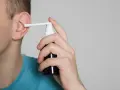 Mężczyzna aplikuje spray do ucha, łagodząc płyn w komórkach wyrostka sutkowatego.