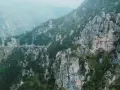 Strada tortuosa che sale verso il passo Barmone, tra rocce imponenti e vegetazione lussureggiante.