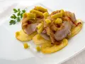 Bonito al horno sobre patatas, con cebolla caramelizada y pimientos verdes. Un plato delicioso y bien presentado.