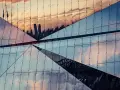 Geometryczna fasada budynku odbija niebo i sylwetki wieżowców. Efekt lustrzane odbicie photoshop.