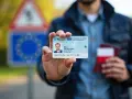 Mężczyzna pokazuje dowód osobisty i paszport. Czy do Francji potrzebny jest paszport? W strefie Schengen dowód wystarczy.