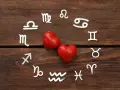 Srebrne symbole znaków zodiaku ułożone w okrąg wokół dwóch czerwonych serc. Wskazują na połączenia znaków zodiaku w miłości.