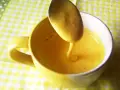Kogel mogel przepis w filiżance, łyżka z gęstym, żółtym kremem spływa do naczynia.